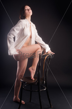Portrait of sexy young woman sitting on chair over black background