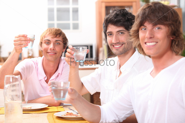 Three young men eating a meal together and drinking water, stock photo