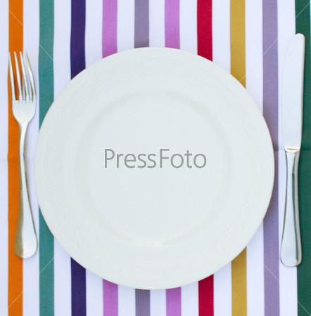 empty white plate with knife and fork on tablecloth