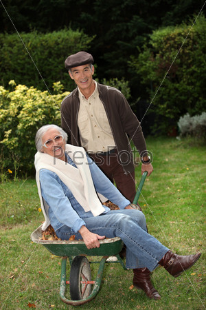 Older couple messing around with a wheelbarrow