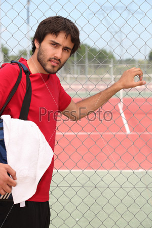 Young man outside a tennis court