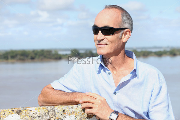 Grey-haired man stood by river-front