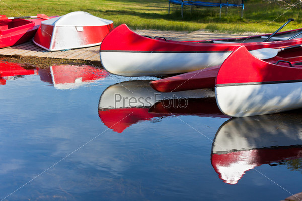 Red and White Canoes and Boats with Paddles and Its Reflection in a Water