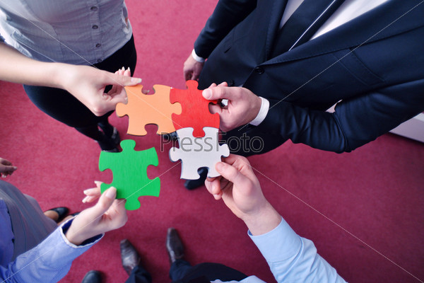 Group of business people assembling jigsaw puzzle and represent team support and help concept, stock photo