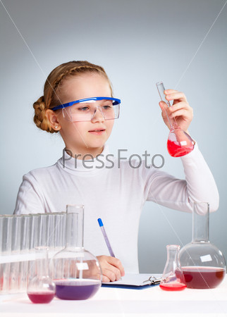 A little girl looking at chemical sample in a flask