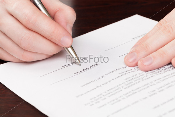 Business men signing contract with silver pen on brown table
