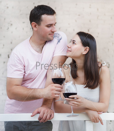 Young happy couple enjoying a glasses of red wine on terrace