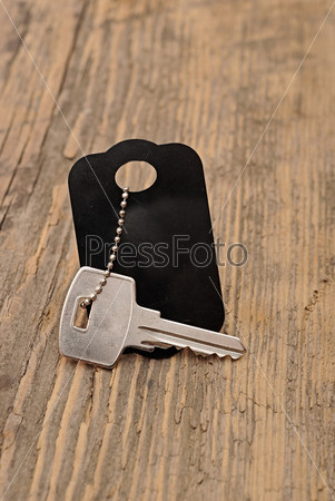 silver key with blank tag wooden background. space for your text