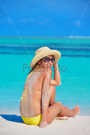 happy young beautiful asian woman relax on sand at tropical beach with cristal clear sea in background