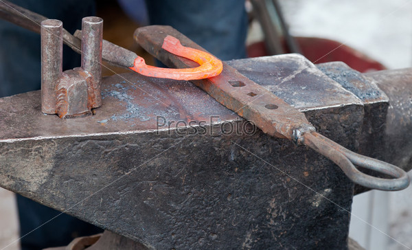 Blacksmith forging a horseshoe on an anvil