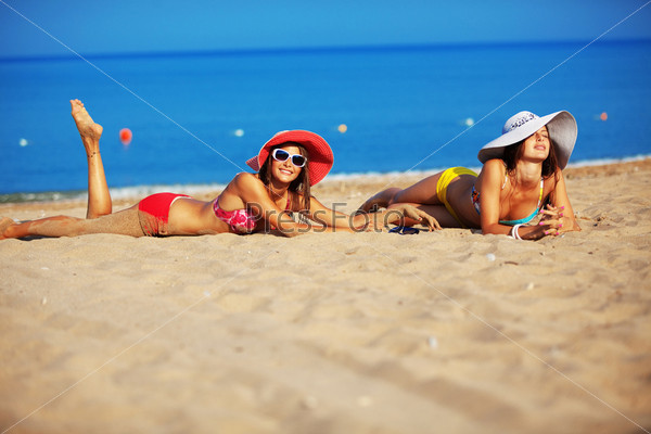 Beautiful young girls resting at the beach in hot summer