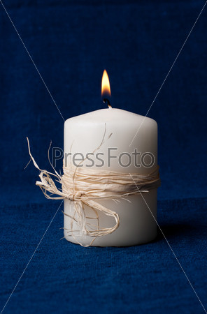 White candle that is lit on a dark blue background