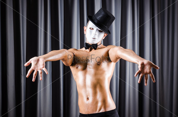Muscular actor with mask against curtain, stock photo