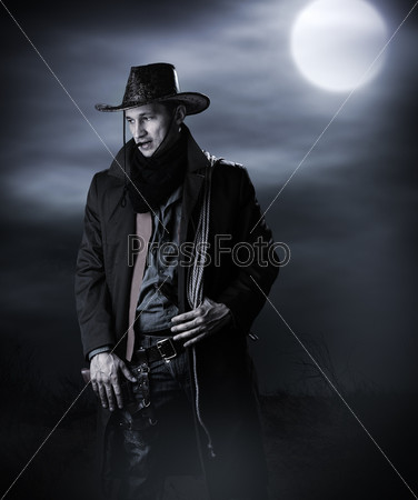 Handsome man in cowboy costume stay in steppe at night with full moon. Vampire Hunter