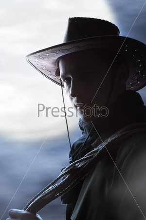 silhouette of Handsome man in cowboy costume stay in steppe at night with full moon. Vampire Hunter