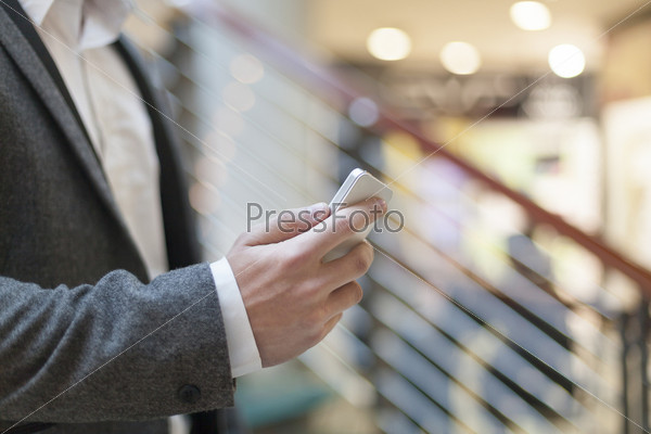 Man with smart phone on hand, blurred background, business building interior