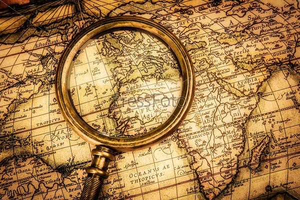 Vintage still life. Vintage magnifying glass lies on an ancient world map