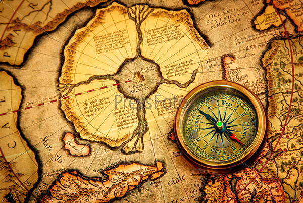 Vintage compass lies on an ancient map of the North Pole.