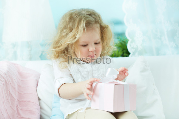 Adorable child unwrapping a birthday gift at home
