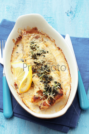 Cooked fish with spinach in baking dish on blue wooden table