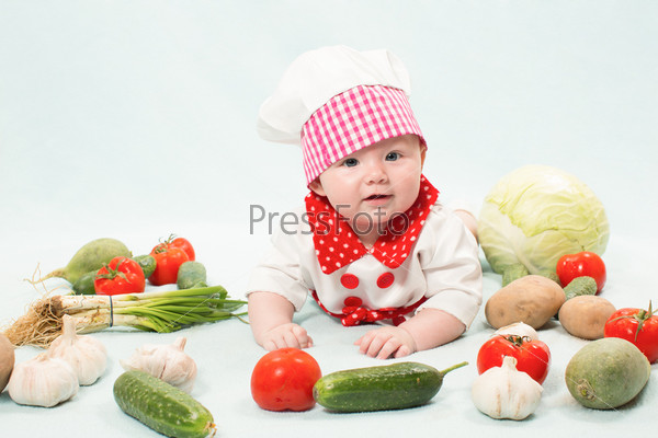 Baby girl wearing a chef hat with vegetables