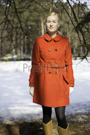 Young woman in red coat under spruce