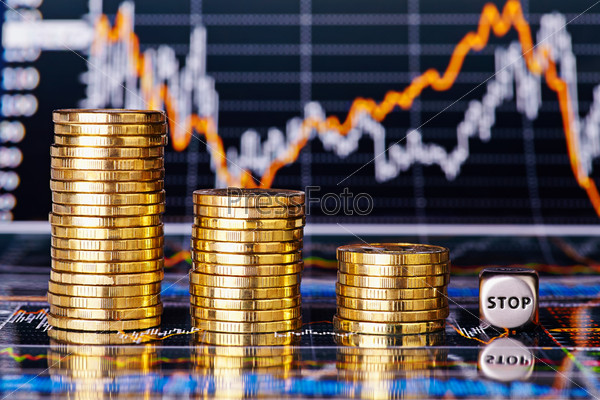 Downtrend financial chart, stacks of golden coins and dices cube with the word STOP. Selective focus