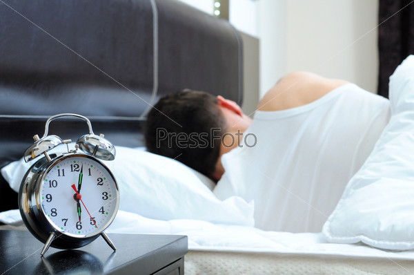 Man sleeping with alarm clock in foreground