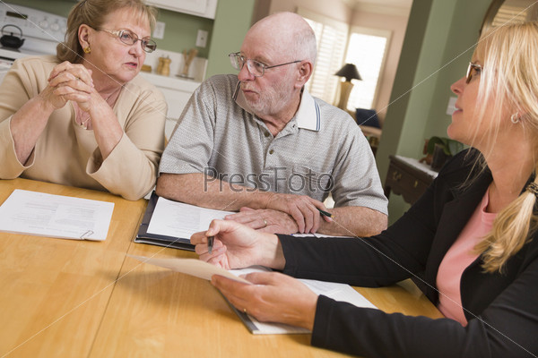 Senior Adult Couple Going Over Papers in Their Home with Agent.
