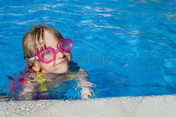 Little girl swimming in pool with goggles