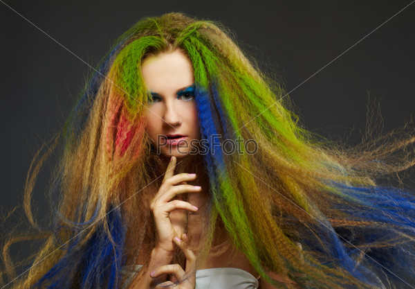 portrait of young beautiful red-haired woman with long curly hair colored with green blue and red
