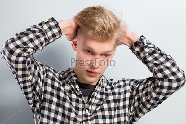 Young handsome guy with hand on head over grey background