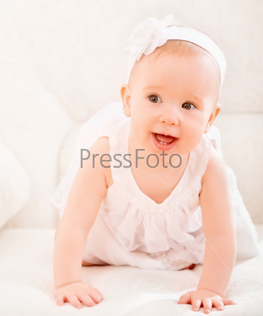 happy little cute baby girl in a white dress and with flower smiling at home