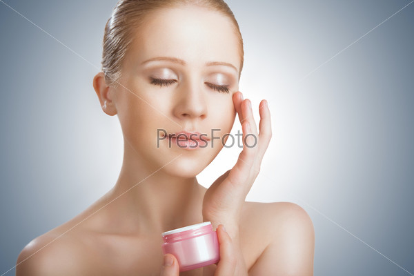skin care. face of a happy beauty healthy girl with eyes closed with jar of cream