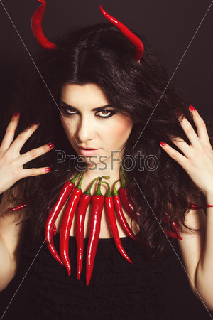 Devil. young woman portrait with red hot and spicy peppers