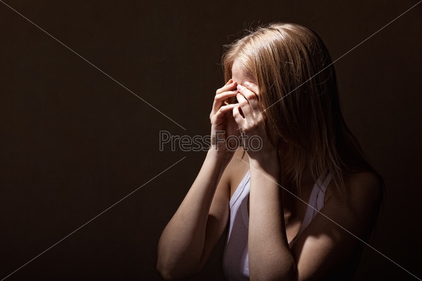 Young crying woman on a dark background