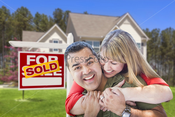 Happy Hugging Mixed Race Couple in Front of Sold Home For Sale Real Estate Sign and House.