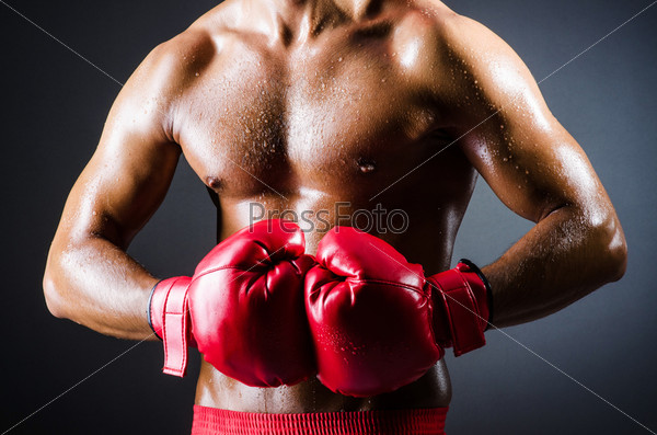 Боксер с красными перчатками в темной комнате