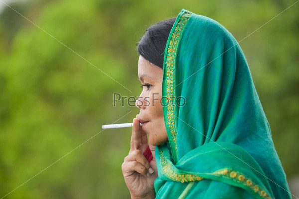 South-east asian woman with head dress smoking