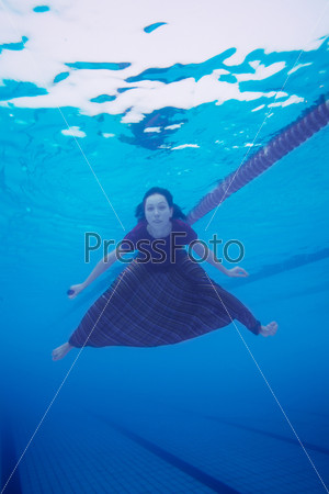Woman swimming in the pool in  clothes - underwater shoot