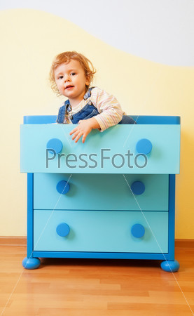 Kid sitting inside blue opened cabinet box