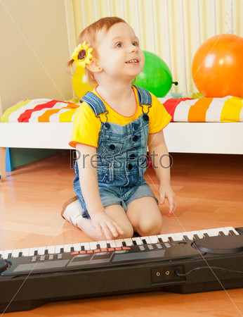 Little girl playing piano sitting on the floor