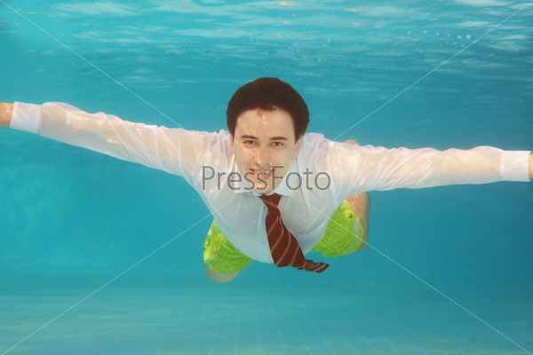 Business man swimming underwater in the pool wearing white shirt and red tie