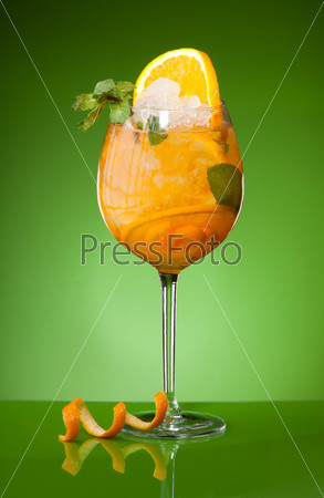 Fresh orange drink with ice and mint on green background