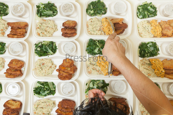 Multiple portions of fresh food being dished out onto individual serving trays