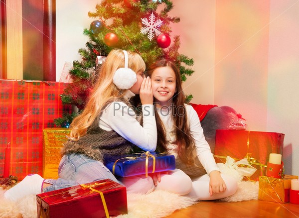 Two 8 years old girls sharing each other secrets on Christmas Eve, stock photo