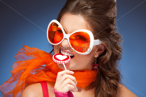 Woman with trendy glasses and red scarf eating lollipop