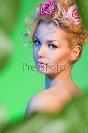 Wedding portrait of woman with curly blond hair on green background turning her head back