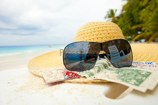 Соломенная шляпа, деньги и очки на пляже