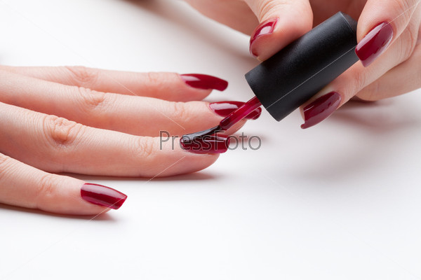 Painting fingernail with red enamel close-up